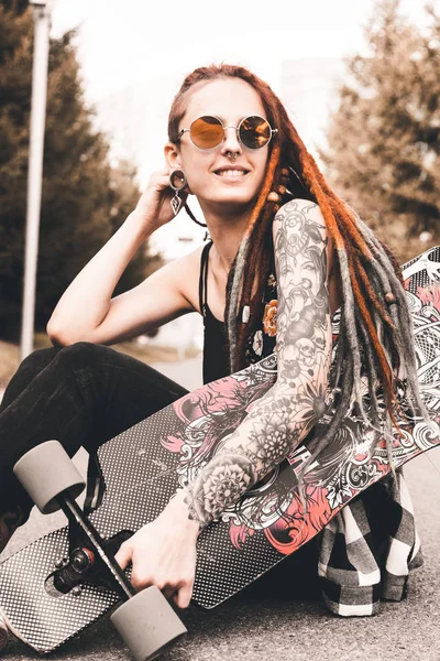 UFA, RÚSSIA - 12 de setembro de 2018 Foto editorial de uma jovem com tatuagens e dreadlocks sentada no parque — Fotografia de Stock