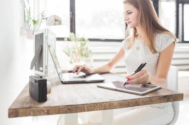 Evde çalışan genç iş kadını ve berabere tablette. Yaratıcı İskandinav tarzı çalışma alanı