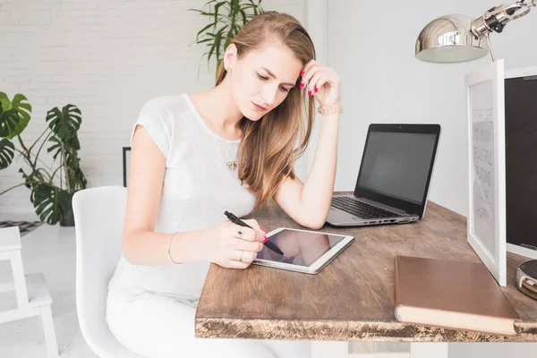 Νεαρή γυναίκα που εργάζεται στο σπίτι και ισοπαλίες στο tablet. Δημιουργική σκανδιναβικό στυλ χώρου εργασίας — Φωτογραφία Αρχείου
