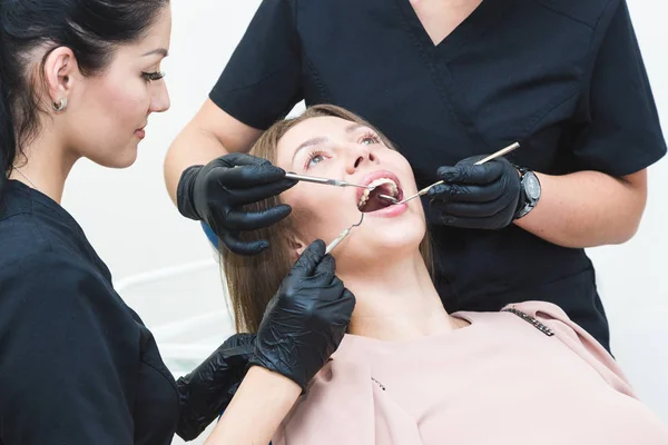 Clínica dentária. Recepção, exame do paciente. Cuidado com os dentes. Jovem é submetida a um exame odontológico por um dentista — Fotografia de Stock