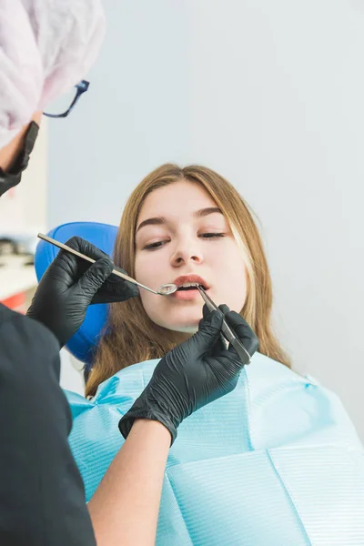 Clínica dental. Recepción, examen del paciente. Cuidado de los dientes. Chica joven se somete a un examen dental por un dentista — Foto de Stock