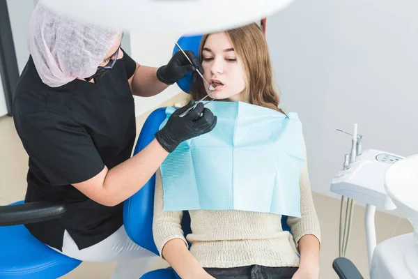 Clínica dentária. Recepção, exame do paciente. Cuidado com os dentes. Jovem se submete a um exame dentário por um dentista — Fotografia de Stock