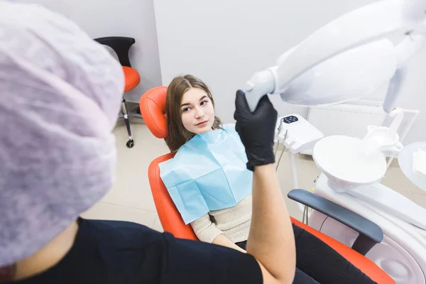 Clínica dental. Recepción, examen del paciente. Cuidado de los dientes. Dentista femenina en consultorio dental hablando con paciente chica . — Foto de Stock