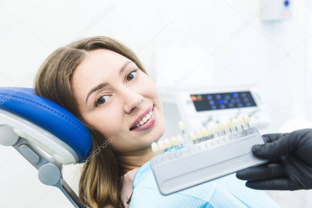 Dental clinic. Reception, examination of the patient. Teeth care. Dentist with tooth color samples choosing shade for women patient teeth at dental clinic