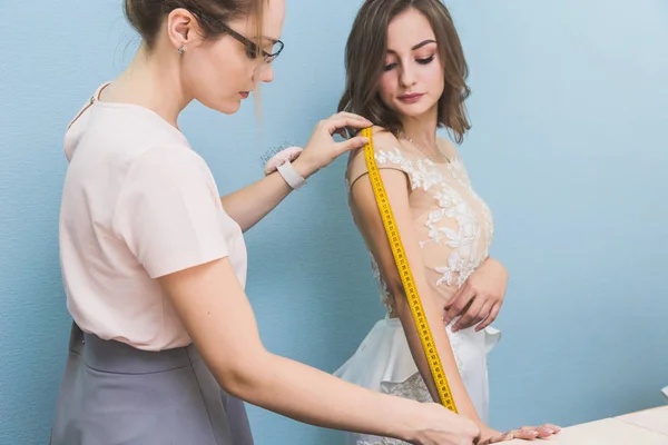 Sewing workshop. Seamstress at work. Seamstress takes measurements of a wedding dress