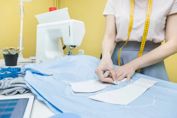 Sewing workshop. Seamstress at work. Marking and cutting fabric.