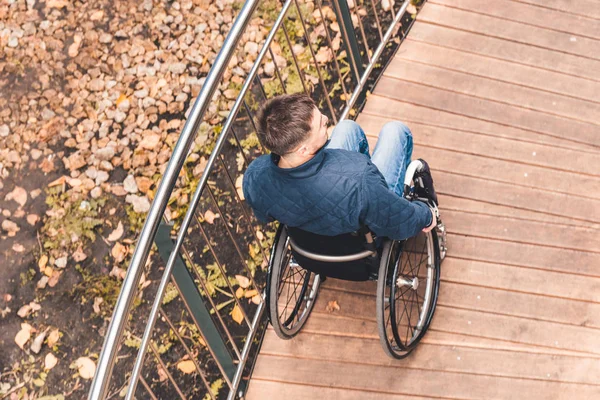 Człowiek na wózku inwalidzkim używać rampy dla wózków inwalidzkich. — Zdjęcie stockowe