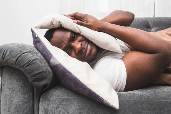 Sleepy guy waking up early after hearing alarm clock signal and does not want to get up.