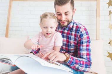 Baba ve kızı birlikte oturup kitap okumak.