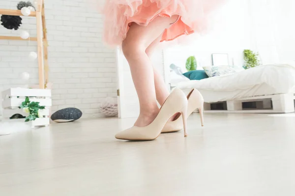 Cute little girl with her mothers shoes at home.