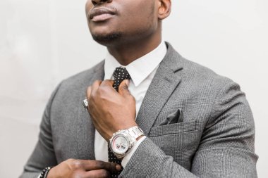 Beyaz bir arka plan üzerinde bir kravat bağlama gri takım elbiseli Genç Afrikalı-Amerikalı işadamı.