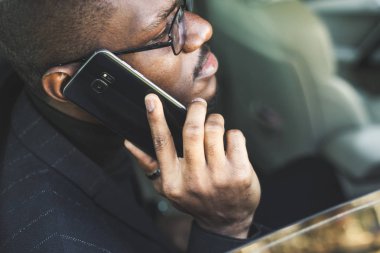 Telefonda konuşan genç başarılı işadamı pahalı bir arabanın arka koltuğunda oturuyor. Görüşmeler ve iş toplantıları.