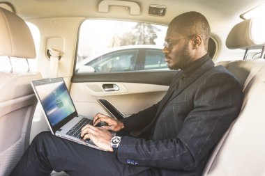 Bir iş kıyafeti adam deri iç ile pahalı bir araba salonda laptop yazmak.