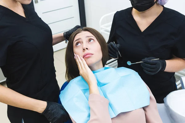 Dental clinic. Reception, examination of the patient. Teeth care. Young woman feels pain at the dentist