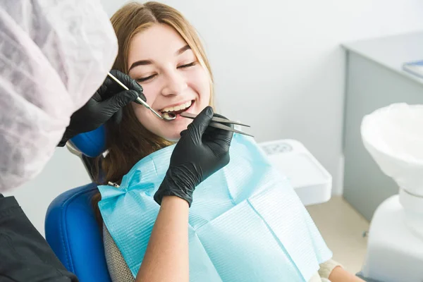 Clínica dental. Recepción, examen del paciente. Cuidado de los dientes. Chica joven se somete a un examen dental por un dentista — Foto de Stock