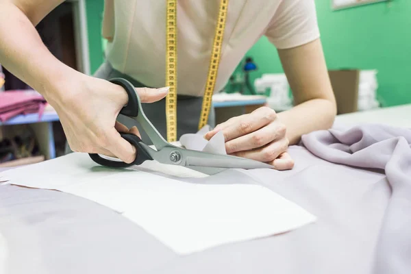 Sewing workshop. Seamstress at work. Marking and cutting fabric.