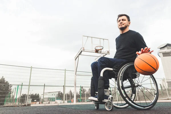 Jonge man in een rolstoel spelen basketbal. — Stockfoto