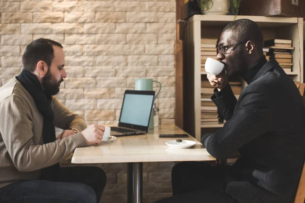 Mångkulturella afrikanska och kaukasiska affärs män förhandla i ett kafé. — Stockfoto