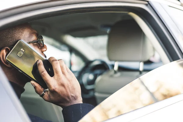 Młody biznesmen mówi na telefon siedzi na tylnym siedzeniu drogiego samochodu. Negocjacje i spotkania biznesowe. — Zdjęcie stockowe