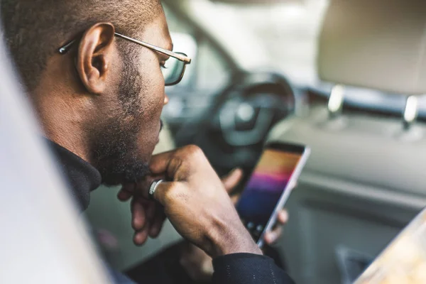 Fiatal sikeres üzletember beszél a telefon ül a hátsó ülésen egy drága autót. Tárgyalások és üzleti találkozók. — Stock Fotó