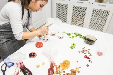 Bir şekerleştirici üç bardak içinde bir saçma hazırlar. Mutfaktaki beyaz masada tatlılar vardır. Ev yapımı pasta kavramı, yemek pastaları.