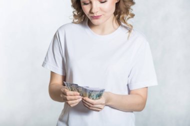 Pensive genç kadın bize dolar para beyaz arka plan üzerinde sayar.