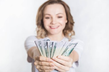 Mutlu genç gülümseyen kadın beyaz arka planda bize dolar para tutun.