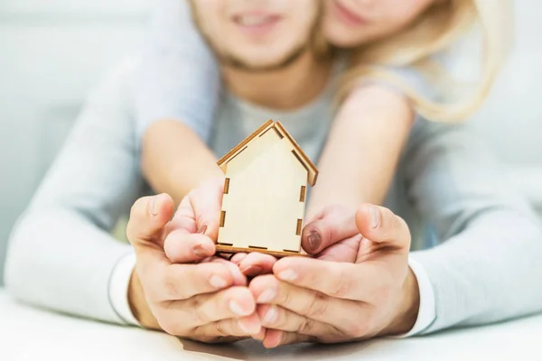 Preciosa pareja joven sosteniendo un diseño de la casa en sus manos extendidas. El concepto de comprar un nuevo apartamento . — Foto de Stock