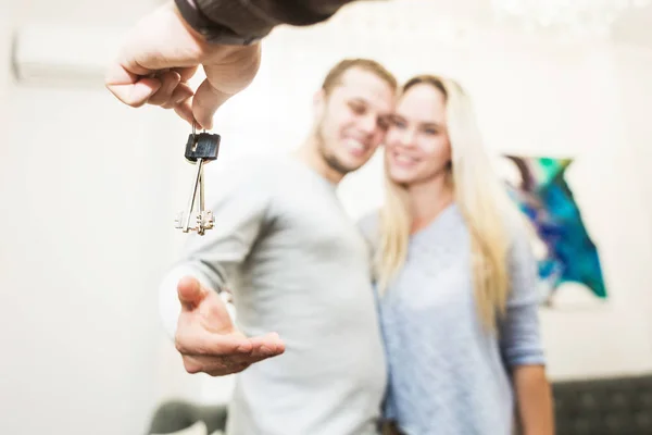 Una encantadora pareja joven obtiene las llaves de su nuevo apartamento de un agente de bienes raíces . — Foto de Stock