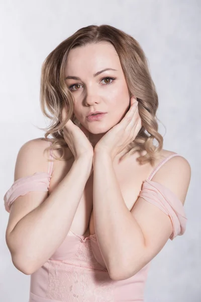 Retrato de hermosa joven elegante mujer en vestido de novia de color rosa pálido con escote grande, sobre un fondo blanco . — Foto de Stock