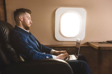Onun özel jet bir sandalyede otururken bir laptop üzerinde çalışan çekici ve başarılı işadamı.