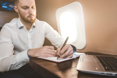 Beyaz gömlekli çekici ve başarılı bir iş adamı özel jetinin koltuğunda oturuyor..