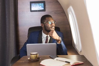 Onun özel jet sandalyede otururken gözlük bir dizüstü bilgisayar üzerinde çalışan çekici ve başarılı Afrikalı Amerikan işadamı.