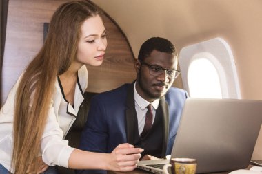 Genç başarılı Afrikalı-Amerikan işadamı gözlük ve çekici bir kadın iş arkadaşı Sarışın özel bir Jet. Hizmet ve uçuş birinci sınıf