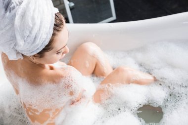 Genç çekici bir kız banyoda rahatlatır ve güzel bir ışık iç zemin karşı oturmaktadır. Cilt Bakımı ile güzellik ve sağlık için spa uygulamaları