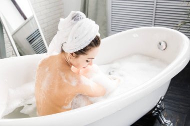 Genç çekici bir kız banyoda rahatlatır ve güzel bir ışık iç zemin karşı oturmaktadır. Cilt Bakımı ile güzellik ve sağlık için spa uygulamaları