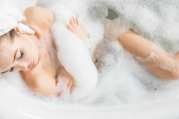 Una giovane ragazza attraente si rilassa in bagno e riposa sullo sfondo di un bellissimo interno leggero. Trattamenti Spa per la bellezza e la salute con la cura della pelle — Foto Stock