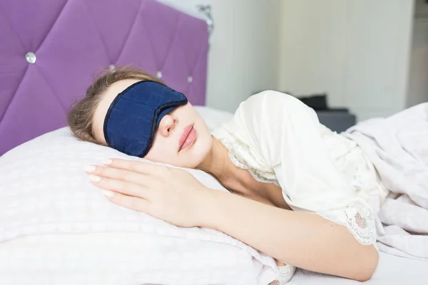 Gadis muda cantik tidur di pagi hari di tempat tidurnya dengan masker wajah. kesehatan dan keindahan — Stok Foto