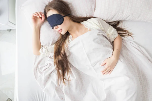Belle jeune fille qui dort le matin dans son lit avec un masque facial. Vue d'en haut — Photo