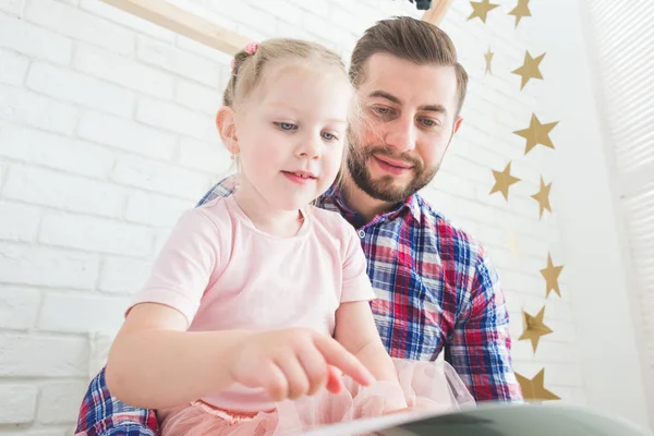 Papá e hija se sientan juntos y leen un libro . — Foto de Stock