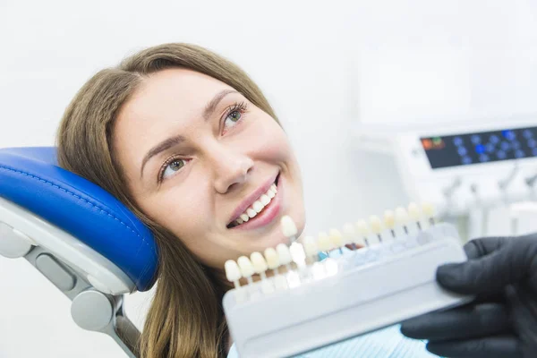 Clínica dental. Recepción, examen del paciente. Cuidado de los dientes. Dentista con muestras de color de dientes eligiendo la sombra para las mujeres dientes de pacientes en la clínica dental — Foto de Stock