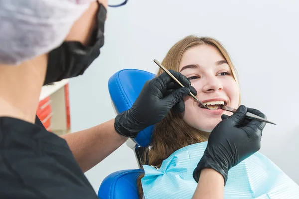 Clínica dentária. Recepção, exame do paciente. Cuidado com os dentes. Jovem se submete a um exame dentário por um dentista — Fotografia de Stock