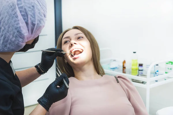 Dental clinic. Reception, examination of the patient. Teeth care. Young woman undergoes a dental examination by a dentist