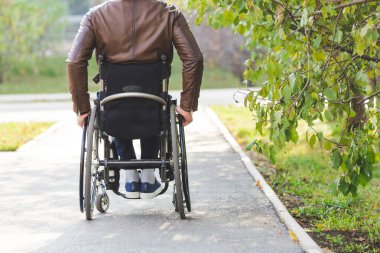 Genç biri tekerlekli sandalyede park yol boyunca rides.