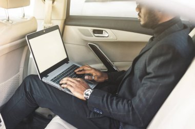 Bir iş kıyafeti adam deri iç ile pahalı bir araba salonda laptop yazmak.