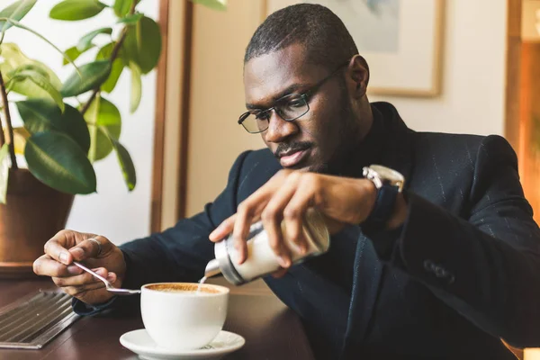 Ung stilig mörkhyad affärsman dricker kaffe på ett café. — Stockfoto
