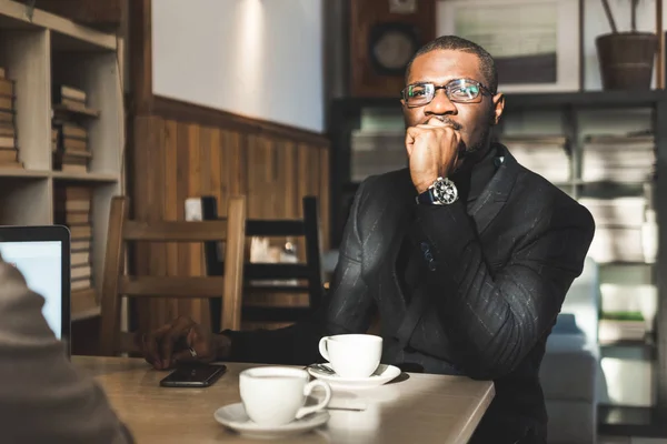 Jeune homme d'affaires à la peau foncée dans un café avec une tasse de thé . — Photo