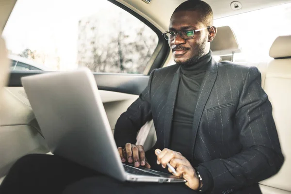 Man in a business suit write on laptop in the salon of an expensive car with leather interior.