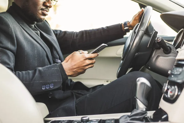 Egy üzletember vezetői egy drága autót tart a mobil telefon a kezében. Elhamarkodott élet. — Stock Fotó