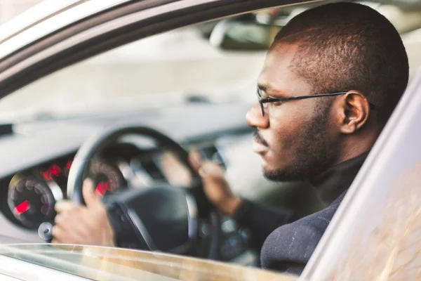 Ένας νεαρός επιχειρηματίας με κουστούμι κάθεται στο τιμόνι ενός ακριβούς αυτοκινήτου. — Φωτογραφία Αρχείου